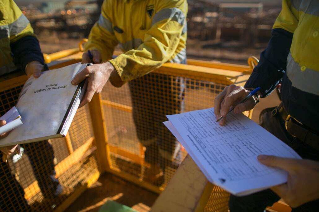 Miner supervisor checking reviewing document before issued sigh of working at height permit JSA risk assessment on site prior to performing high risk work on construction mine site